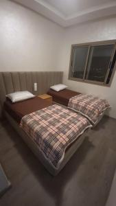 2 camas en una habitación con ventana en Appartement Calme avec Piscine Mohemmadia Zenata, en Aïn Harrouda