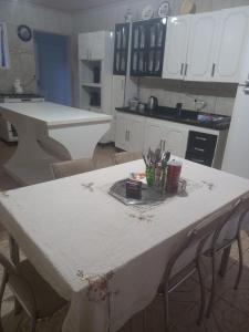 a kitchen with a white table with chairs in it at Pousada Estrela Azul in São Gabriel
