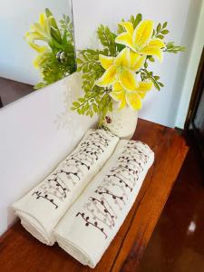 Mkayamba House في ماليندي: وسادتين على طاولة مع مزهرية مع الزهور الصفراء
