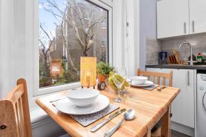 une cuisine avec une table en bois et une fenêtre dans l'établissement Olympia Kensington Stay Studio, à Londres