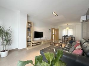ein Wohnzimmer mit einem schwarzen Ledersofa und einem TV in der Unterkunft Casa Jimena in Avila