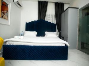 a bedroom with a large bed with a blue headboard at The Duch Apartments in Lagos