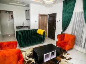 sala de estar con sofá verde y 2 sillas de color naranja en The Duch Apartments, en Lagos