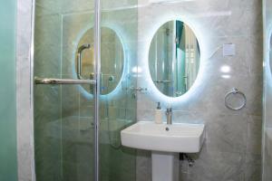 a bathroom with a sink and a shower with a mirror at The Duch Apartments in Lagos
