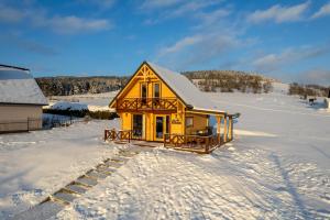提利茲的住宿－Domek Tylicz Widoki，雪中的一个黄色小房子