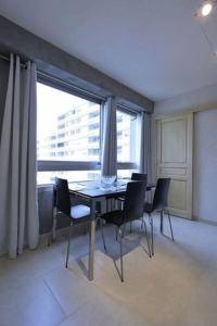 a dining room with a table and chairs and a large window at Appartement avec ascenseur LA DÉFENSE in Courbevoie
