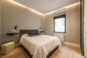 Habitación blanca con cama y ventana en En el corazón de Madrid, casa Moderna, en Madrid