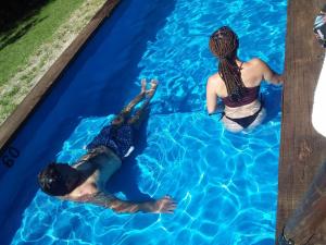 2 persone che nuotano in una piscina di Cabañas Canluma a Villa Giardino