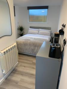 a small bedroom with a bed and a refrigerator at Payne’s Pad in Poole