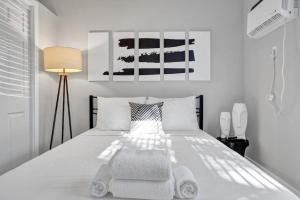 een witte slaapkamer met een wit bed en een stoel bij Rustic Retreats Cozy 1BR For 4 Guests Minutes From Las Olas in Fort Lauderdale