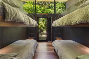 two bunk beds in a room with a window at Kawakawa House - Piha Holiday Home in Auckland