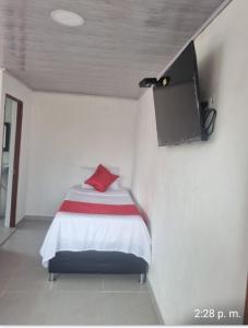 a bedroom with a bed with a tv on the wall at HOTEL ISMAEL de la VILLA in Tinjacá