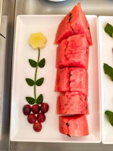 a white plate with watermelon and grapes on it at Hotel Stelati in Jaguariúna