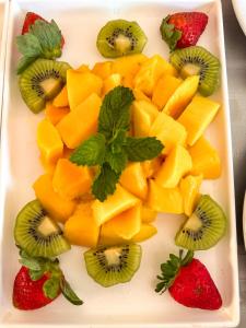 a plate of fruit with kiwis and kiwi and strawberries at Hotel Stelati in Jaguariúna