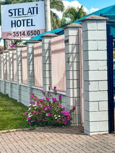 a sign for a hotel with pink flowers next to a fence at Hotel Stelati in Jaguariúna