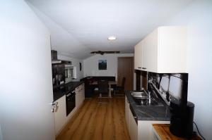 a kitchen with white cabinets and a wooden floor at Haus Jakob in Filzmoos