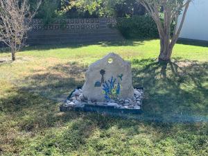 a rock sitting in the grass next to a tree at Stay near Beautiful San Felipe Creek. in Del Rio