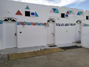 a white building with white doors and colorful tiles on it at Roma House in Aswan
