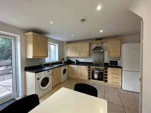 een keuken met houten kasten en een witte koelkast bij Chervil House by YourStays in Newcastle under Lyme