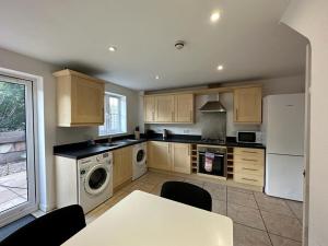 a kitchen with wooden cabinets and a white refrigerator at Chervil House by YourStays in Newcastle under Lyme