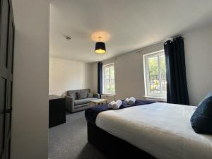 een slaapkamer met een bed, een bank en een raam bij Chervil House by YourStays in Newcastle under Lyme