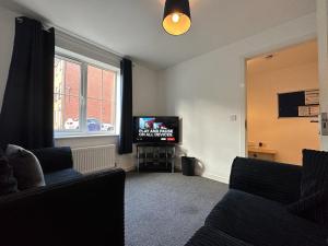 een woonkamer met 2 banken en een televisie bij Chervil House by YourStays in Newcastle under Lyme