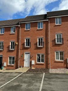 a brick building with a white door in a parking lot at Chervil House by YourStays in Newcastle under Lyme