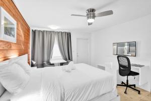 Habitación blanca con cama blanca y escritorio. en Waves Beach Town Studio Apartment en Pompano Beach