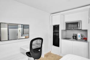 Habitación blanca con silla y microondas en Waves Beach Town Studio Apartment en Pompano Beach