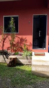 a red building with two windows and a tree stump at Pousada Recanto da Lu in Paraty