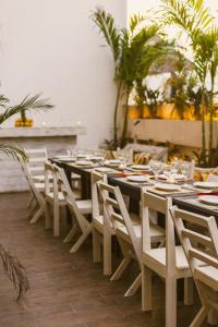 una sala da pranzo con tavoli, sedie e palme di Gardenia Collective a Tulum