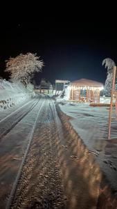 een met sneeuw bedekte treinbaan met 's nachts een treinstation bij Domek drewniany w górach Jacuzzi & Balia - Osada Chełm in Stróża
