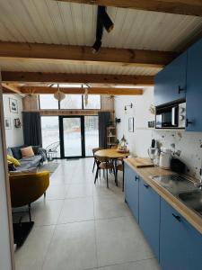 a kitchen with blue cabinets and a table with chairs at Trzy Stodoły - Kraina Łąk domki całoroczne na Roztoczu in Narol