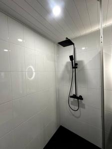 a shower in a white tiled bathroom with a shower at Kotimaailma Apartments#4 - Moderni, tilava kaksio keskustassa in Seinäjoki