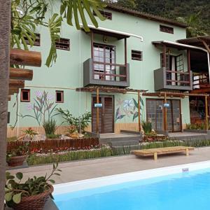 una casa con piscina frente a ella en RAPANUI POUSADA Ubatuba, en Ubatuba