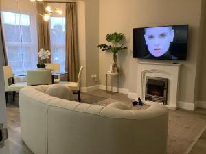 a living room with a white couch and a fireplace at GREATER LONDON APARTMENT in London
