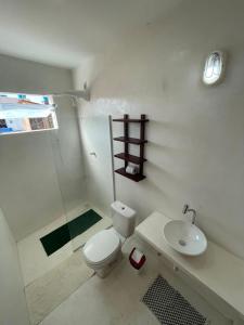 La salle de bains blanche est pourvue de toilettes et d'un lavabo. dans l'établissement Suítes Modernas no Centro da Praia da Pipa, à Pipa