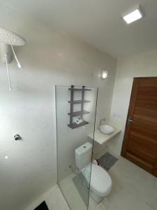 La salle de bains blanche est pourvue de toilettes et d'un lavabo. dans l'établissement Suítes Modernas no Centro da Praia da Pipa, à Pipa
