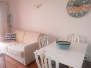 a living room with a table and a couch and a clock at Apartamento Mar Azul in Lagos