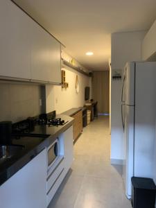 a kitchen with white cabinets and a refrigerator at FLAT ECO RESORT PRAIA DOS CARNEIROS in Tamandaré