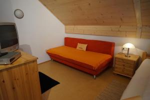 a small bedroom with a bed with an orange blanket at Seminar- und Erlebnishof Das schwarze Schaf in Bad Gams