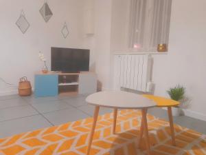 - un salon avec une table et une télévision dans l'établissement Le Fjørd - Appartement confort, rez-de-chaussée, scandinave, parking gratuit, à Bourges