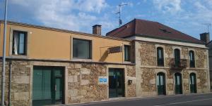 a stone building with glass doors on a street at Hotel Rustico Casa Do Vento in Bayo