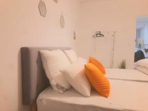 - un canapé blanc avec des oreillers orange dans l'établissement Le Fjørd - Appartement confort, rez-de-chaussée, scandinave, parking gratuit, à Bourges