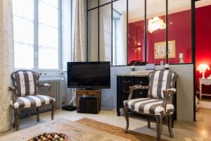 a living room with two chairs and a television at Le Loisy in Dijon