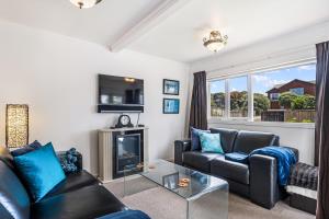 a living room with couches and a fireplace at Tutere Treasure - Waikanae Holiday Home in Waikanae