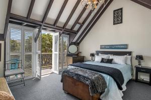 a bedroom with a bed and windows and a chandelier at Tutere Treasure - Waikanae Holiday Home in Waikanae