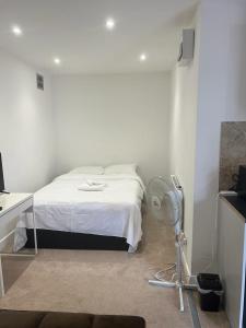 a bedroom with a white bed and a fan at Starlet Property in Wanstead