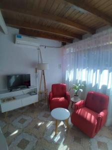 ein Wohnzimmer mit 2 roten Stühlen und einem TV in der Unterkunft Departamento Zapata 5ta Mendoza in Mendoza