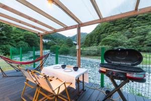 un porche cubierto con parrilla, mesa y sillas en SPRINGS VILLAGE Ashigara-Tanzawa Hot Spring Resort & Glamping - Vacation STAY 42312v en Oyama
